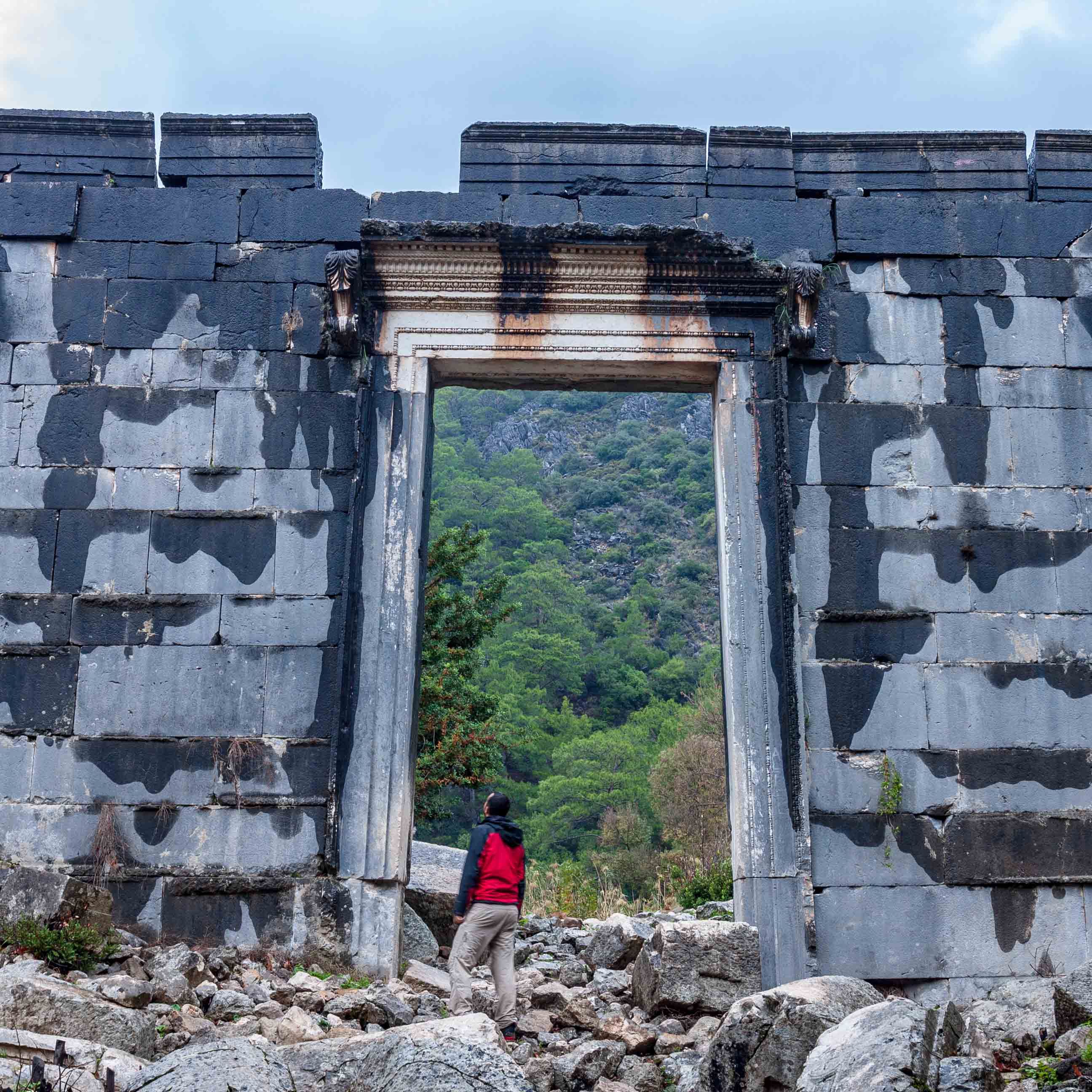 Hiker standing by the giant door of temple in Olympos 