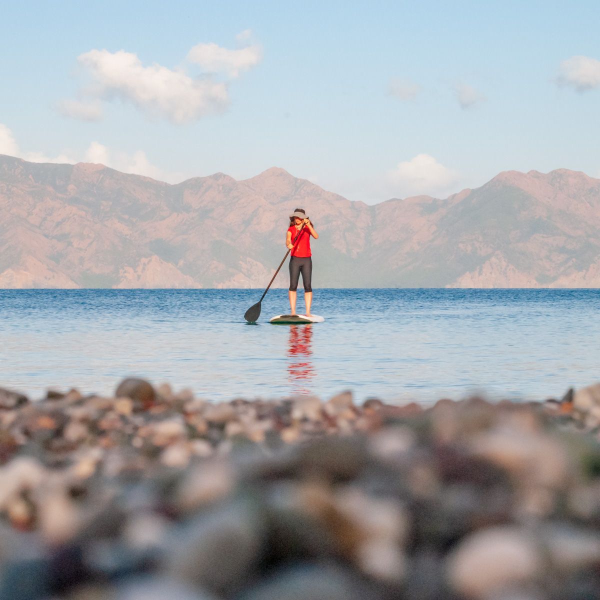 paddle boarder with hills in the background